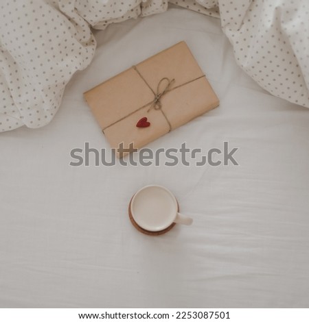 Cup of coffee with milk and gift box in bed with plaid, copy space. Flat lay, top view. morning in bed concept composition