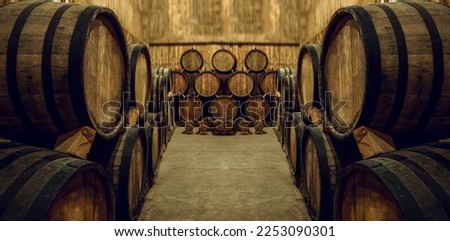 Wine or cognac barrels in the cellar of the winery, Wooden vine or beer barrels in perspective. wine vaults. vintage oak barrels of craft beer or brandy. Royalty-Free Stock Photo #2253090301