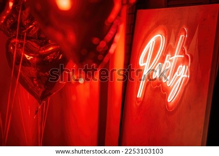 Beautiful place for st valentines holiday with neon letters party design element inside. Logo signage text of color led lamp shine sign light on wall at muffled glamour night room background