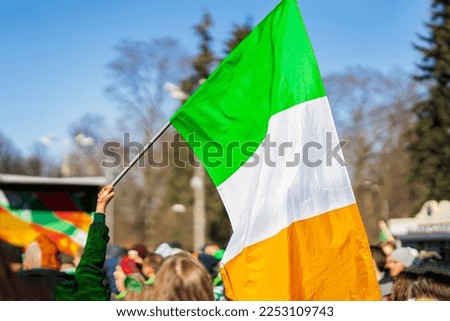 National Flag of Ireland close-up above people crowd people, traditional carnival of St. Patrick's Day in park