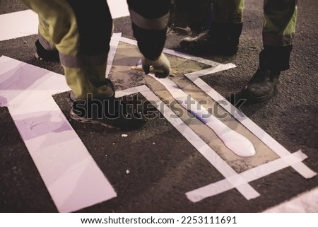 Process of making new road surface markings with a line striping machine, workers improve city infrastructure, demarcation marking of pedestrian crossing with hot melted paint on asphalt pavement