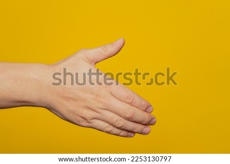 Man stretching out his hand to handshake isolated on a yellow background. Man's hand ready for handshake. Alpha.