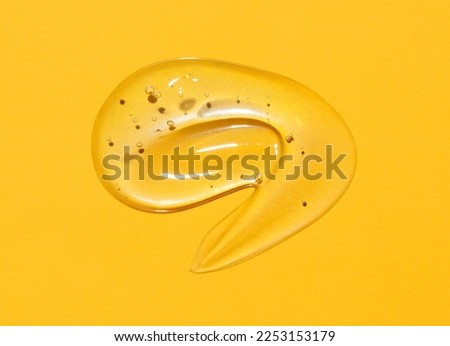 Cosmetic serum gel beauty swatch smear smudge on yellow color background. Skincare beauty product with bubbles texture