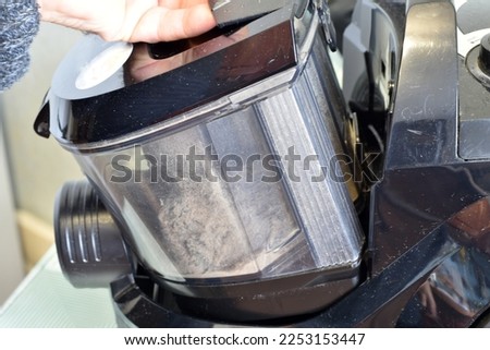 The picture shows the moment of disassembling the vacuum cleaner, removing the dust collector.