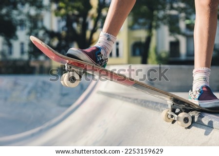 Legs of a skater girl on the skateboard before doing a drop in at the skate park bowl