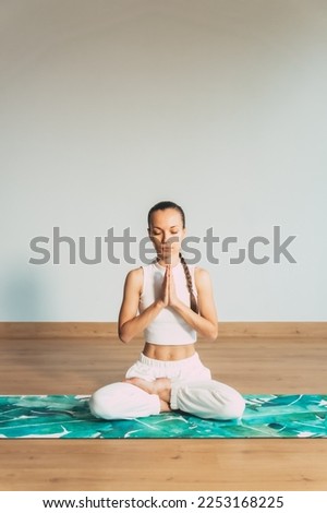 young girl during exercises, asian yoga practice in studio, meditation, on bright background  