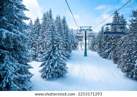 Skiing and snowboarding ski resort background. Ski chairlift and winter panorama at ski resort. View on the ski lift and beautiful snowy mountain with pine trees. Copy space