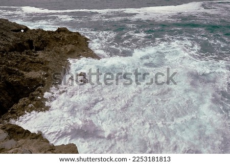 Waves breaking on the shore on a pebble road. water foam, wild waters, texture, ocean, sea, rocks,danger