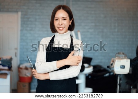 Portrait of a young asian female hairdresser holding qualified haircut tools in her salon for a woman's haircut. Photo job concept for small business owner and haircare. Royalty-Free Stock Photo #2253182769
