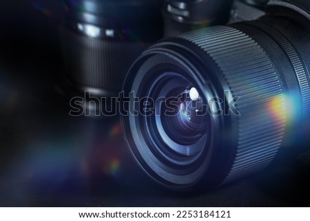 Digital photography, lens of a black camera with reflections and flares against a dark background, technical equipment for business and art, copy space, selected focus, narrow depth of field
