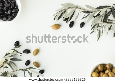 Green and black olives in white bowls next to a bottle with olive oil and leaves on a white background. 
Bottle of cold pressed oil. Traditional Greek and Italian food. Flat lay. Royalty-Free Stock Photo #2253186825