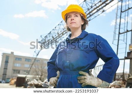 Waist up portrait of empowered woman working at construction site standing against sky with tower crane in background, copy space Royalty-Free Stock Photo #2253191037