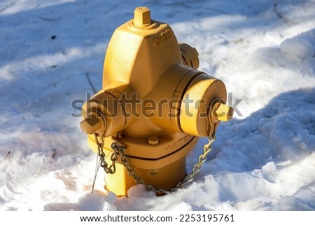 A yellow fire hydrant surrounded with a blanket of snow. Winter weather background.