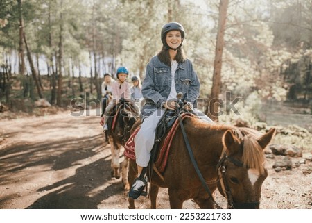 Group of people wearing riding helmets walking on horseback through picturesque places. Royalty-Free Stock Photo #2253221733