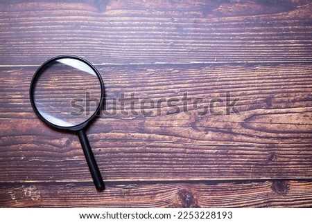 Magnifier placed on a wooden table, there is free space.