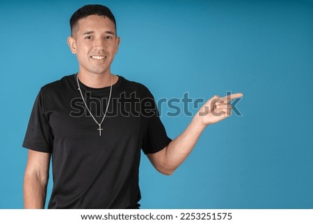 Young man pointing with his hand to the left with a blue background