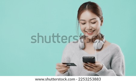 Pretty Asian student girl shop by online shopping application with credit card isolated on mint green screen background.