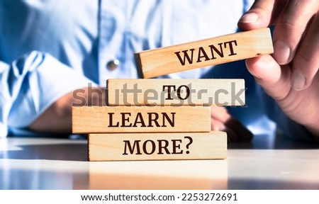 Close up on businessman holding a wooden block with "Want to Learn More?" message Royalty-Free Stock Photo #2253272691