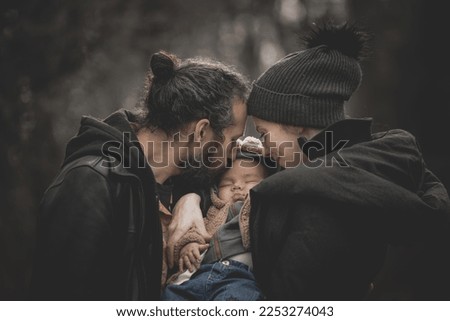 New born family photo shoot in the fall by the woods with father kissing baby