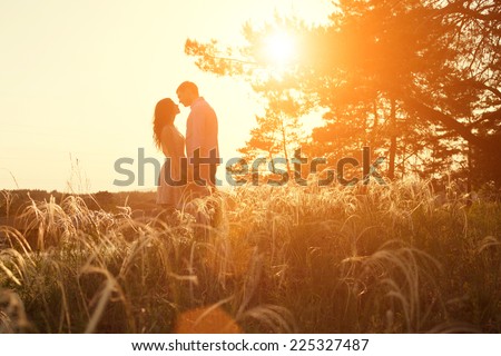 young couple kissing on the background of a sunset in the field Royalty-Free Stock Photo #225327487