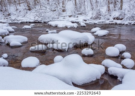 Snow covered stones in the river, winter landscape