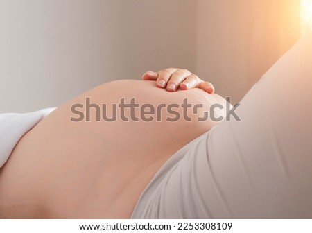 Pregnant girl holds her hand on her stomach. Movement of the baby in the womb during pregnancy. The hiccups of a child. Royalty-Free Stock Photo #2253308109