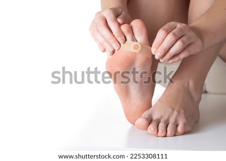 Woman sticks a medical plaster to the plantar wart of the leg to remove dead skin and calluses, close-up Royalty-Free Stock Photo #2253308111