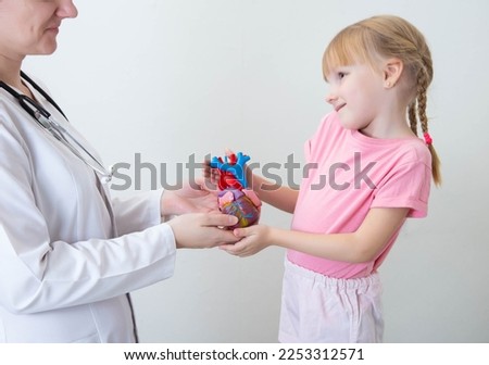 A doctor and a beautiful girl 5 years old are holding a mock-up of a heart. Pediatric cardiac surgery, congenital heart disease, cardiologist Royalty-Free Stock Photo #2253312571