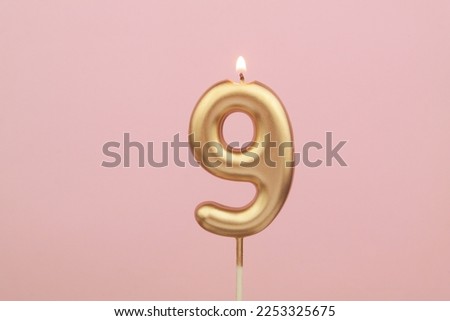 Golden birthday candle shaped as number 9 on pink background Royalty-Free Stock Photo #2253325675