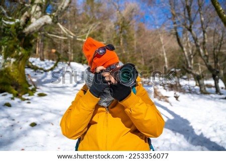 Photographer taking winter photos in the mountains with snow trekking with a backpack