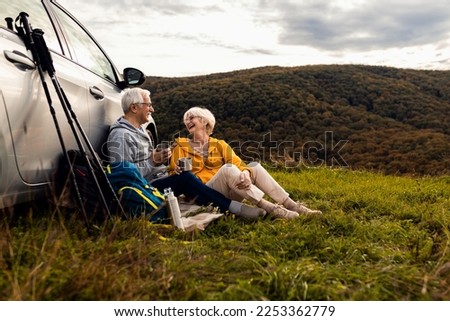 Senior couple sitting against the car, resting after hiking in countryside. Royalty-Free Stock Photo #2253362779
