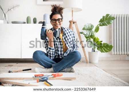 Black woman doing home improvements using screwdriver in new home Royalty-Free Stock Photo #2253367649