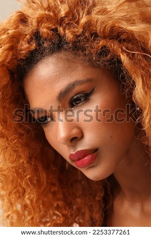 Close-up of young beautiful woman with afro hairstyle posing on the white wall.