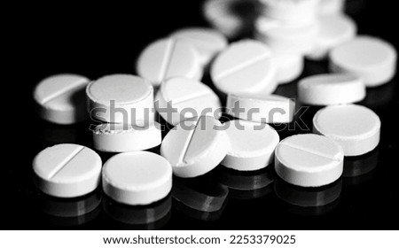 Macro Close up of white painkiller tablet on a reflective black background Royalty-Free Stock Photo #2253379025