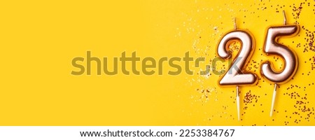 Gold candles in the form of number twenty five on yellow background with confetti. 25 years anniversary celebration. Royalty-Free Stock Photo #2253384767
