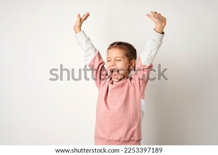 Portrait of cheerful girl with raised hands. Cute little girl raised hands up