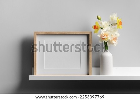 Landscape picture frame mockup on shelf with flowers, blank mockup with copy space