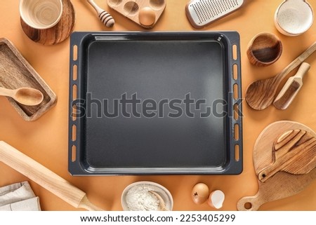 Baking tray with utensils on beige background Royalty-Free Stock Photo #2253405299