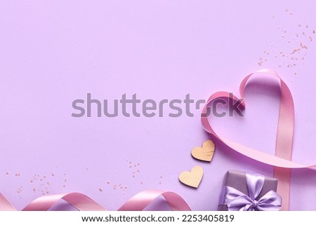 Ribbon with hearts and gift on lilac background. Valentine's Day celebration