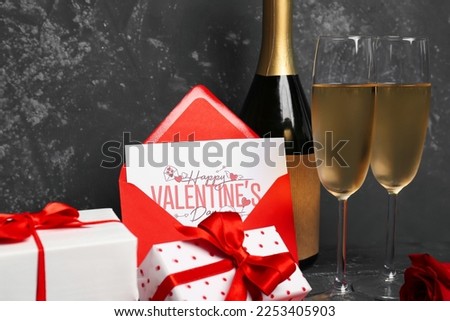 Glasses of champagne, bottle, envelope and gift boxes on dark table. Valentine's Day celebration