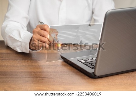 Electronic signature or e-signature. A businesswoman in a white shirt using a pen to sign electronically digital documents on a virtual screen. Technology and paperless office concept Royalty-Free Stock Photo #2253406019