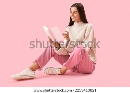 Beautiful woman reading book on pink background