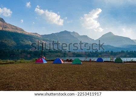Beautiful landscape of camp and tents with hills in the background at Arthur Lake in Bhandardara in Maharashtra, India Royalty-Free Stock Photo #2253411917