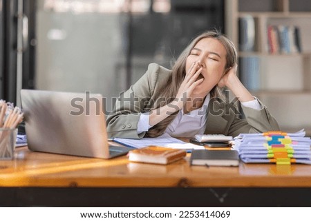 Bored Young business Asian woman sitting at her workplace at the office esk for a long time, Work mental health feel boring and Lazy, Freelance employees sleeping lying, Stress concept. Royalty-Free Stock Photo #2253414069