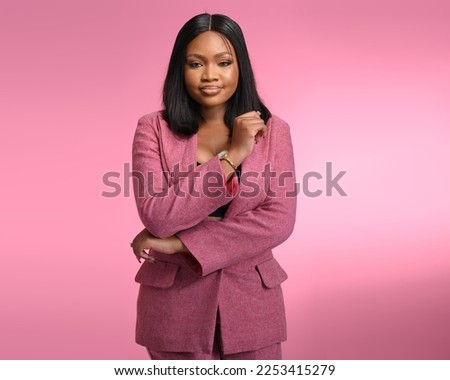 Studio portrait of happy successful confident black business woman. Beautiful young lady in Pink Suit smiling subtly at camera standing isolated on blank solid Pink colour copyspace background Royalty-Free Stock Photo #2253415279