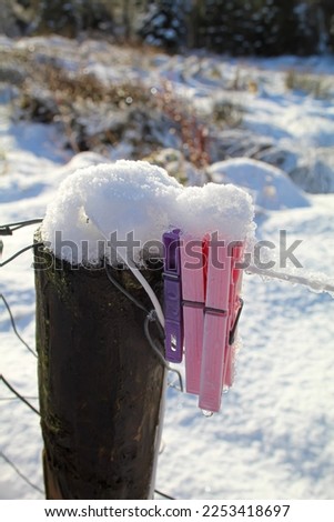 Clothes pegs left on a wire fence, now covered in snow. Objects covered in snow, view in winter season. 