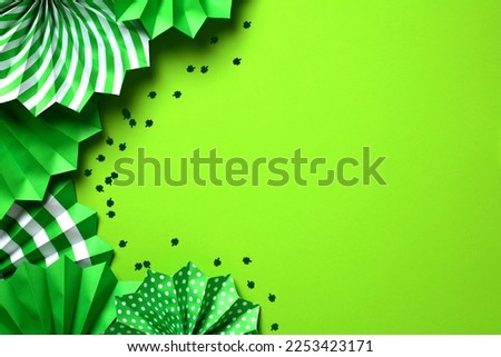 St Patrick's Day background with green paper fans and confetti. Saint Patricks Day greeting card template, banner design, flyer mockup. Flat lay, top view. 