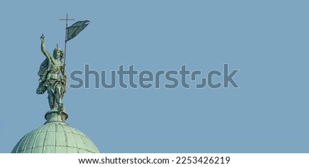 Banner with San Simeone Piccolo Catholic Church, its top dome with statue of Roman man pointing with hand towards sky in Venice, Italy, with copy space solid blue sky background