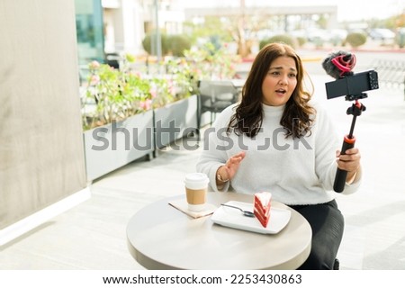 Mexican chubby woman and content creator talking to the camera while filming a video while drinking coffee and eating dessert