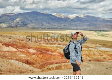 woman tourist in jeans jacket stands against backdrop of landscape on summer day. Sights of Russia, Siberia and Altai Republic, mars field. Tourism, travel and adventure. Kosh-agach, Chagan-Uzun Royalty-Free Stock Photo #2253432149
